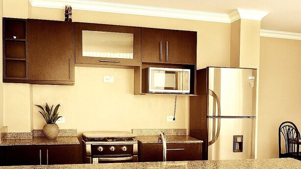 Una cocina moderna con armarios oscuros, un microondas, un refrigerador y una estufa.