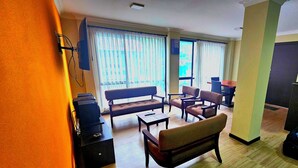 Una sala de estar con un sofá, sillones, una mesa de centro y un televisor.
