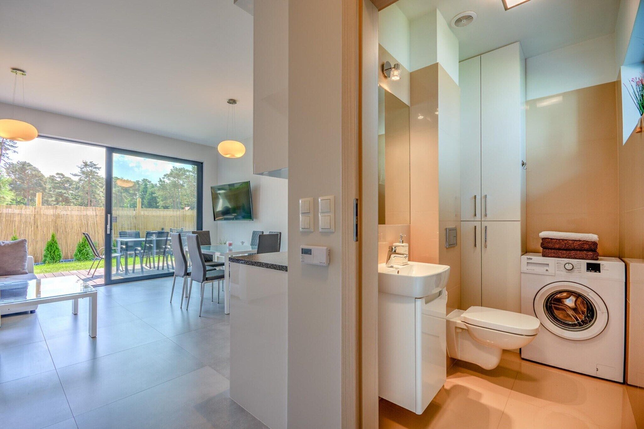 A modern apartment with a dining area, a kitchen, and a bathroom.