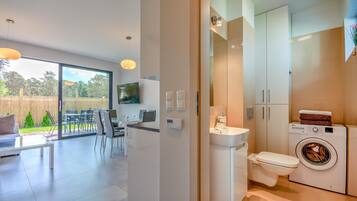 A modern apartment with a dining area, a kitchen, and a bathroom.