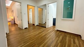 Un couloir doté d’un plancher en bois, de murs blancs et de plusieurs portes donnant accès à différentes pièces.