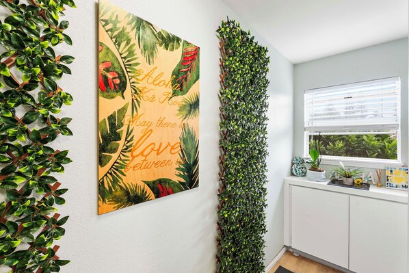 Quarto com uma grande obra de arte com tema tropical, um jardim vertical e uma janela com vista para o verde.