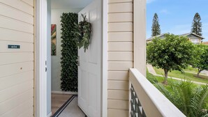 Une porte avec un numéro, une couronne de feuilles vertes et une vue sur un quartier résidentiel avec des arbres et des maisons.