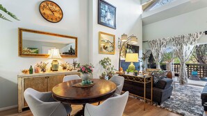 Un coin repas avec une table en bois, quatre chaises, une horloge et un miroir au mur.