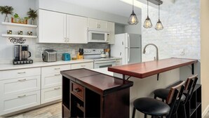 Una cucina moderna con mobili bianchi, un'isola centrale e lampade a sospensione.