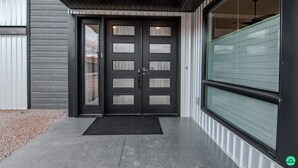 A modern building entrance with a double door, a black mat, and a large window with blinds. - Crimson Place - Moab Home with a Private Pool! (Moab)