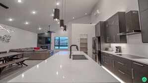 A modern kitchen with a central island, dark cabinetry, and pendant lighting. - Crimson Place - Moab Home with a Private Pool! (Moab)