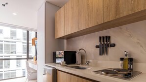 A modern kitchen with wooden cabinets, a stainless steel sink, and a countertop with a coffee machine and utensils. - Nuo by Wynwood House  (Bogotá)