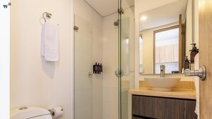 A modern bathroom with a glass-enclosed shower, a white toilet, and a wooden vanity with a large mirror. - Nuo by Wynwood House  (Bogotá)