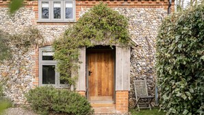 A stone building with a wooden door and a window. - A Pretty Norfolk Cottage (Field Dalling)