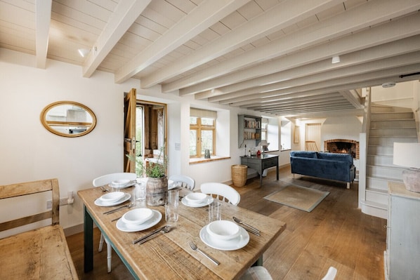 A dining area with a wooden table set for four, a blue sofa, and a fireplace in the background.