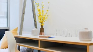 A modern workspace with a desk, chair, and decorative items including a vase with yellow flowers and a clear vase with a white object. - Student Only Canvas The Old Fire Station Birmingham (Birmingham)