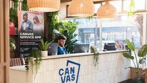A reception area with a sign for Canvas Service App, a laptop, and potted plants. - Student Only Canvas The Old Fire Station Birmingham (Birmingham)