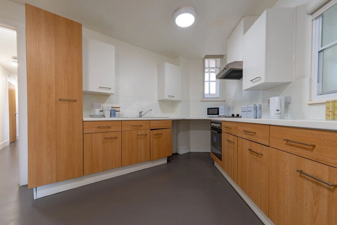 Een moderne keuken met houten kasten, een magnetron en een fornuis.