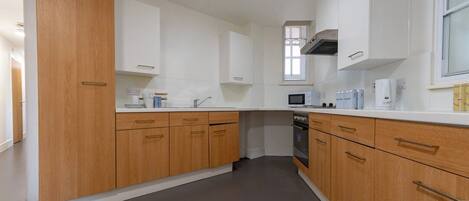 Een moderne keuken met houten kasten, een magnetron en een fornuis.