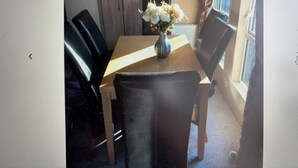 A dining area with a wooden table, black chairs, and a vase with flowers.