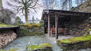 A rustic stone building with a wooden bench and a covered seating area.