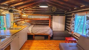 A compact cabin interior with a bunk bed, kitchenette, and a sofa. - Birch Cabin- North Frontenac Lodge (Ompah)