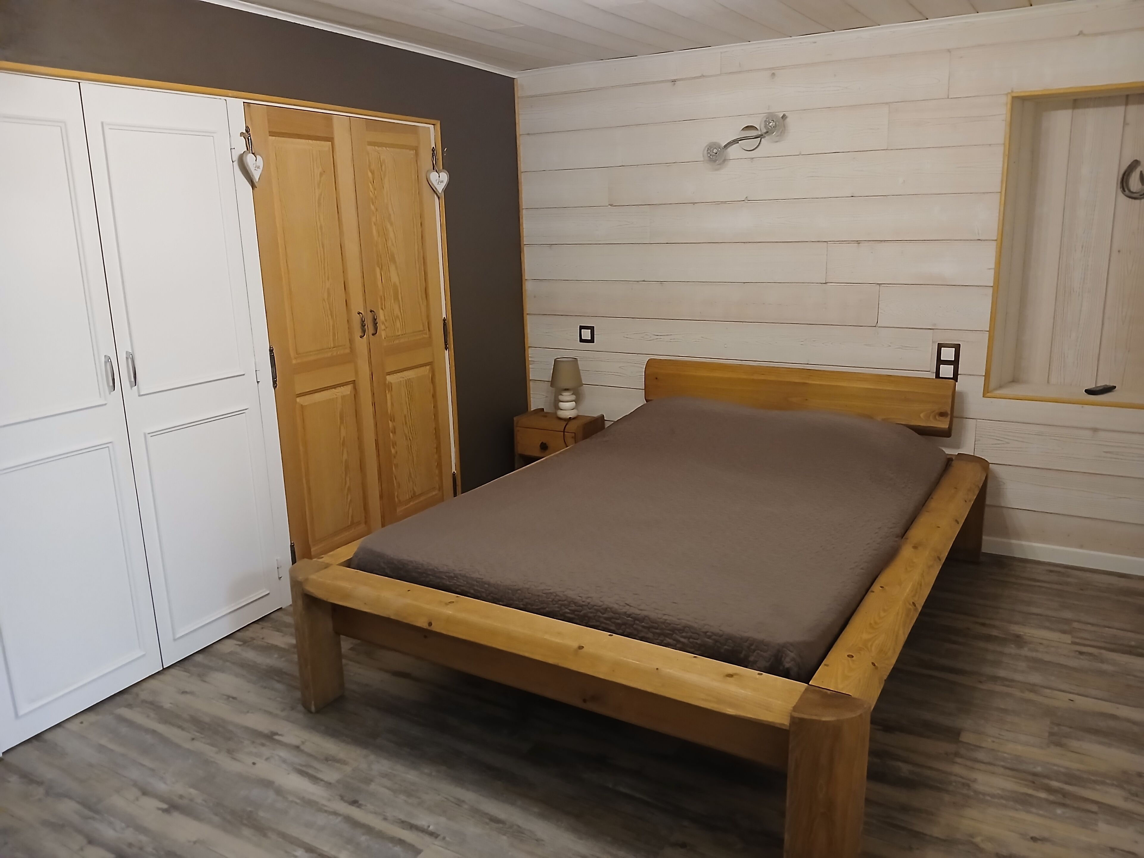Un dormitorio con una cama de madera, un armario y una mesita de noche.