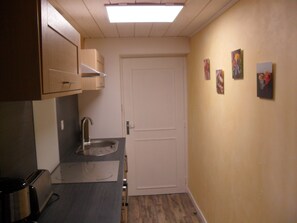 A narrow hallway with a kitchenette on the left, a white door on the right, and a small sink. - Spacious house, private pool, 4 bedrooms, Vallon-Pont-d'Arc, Ardèche (VALLON PONT D'ARC)