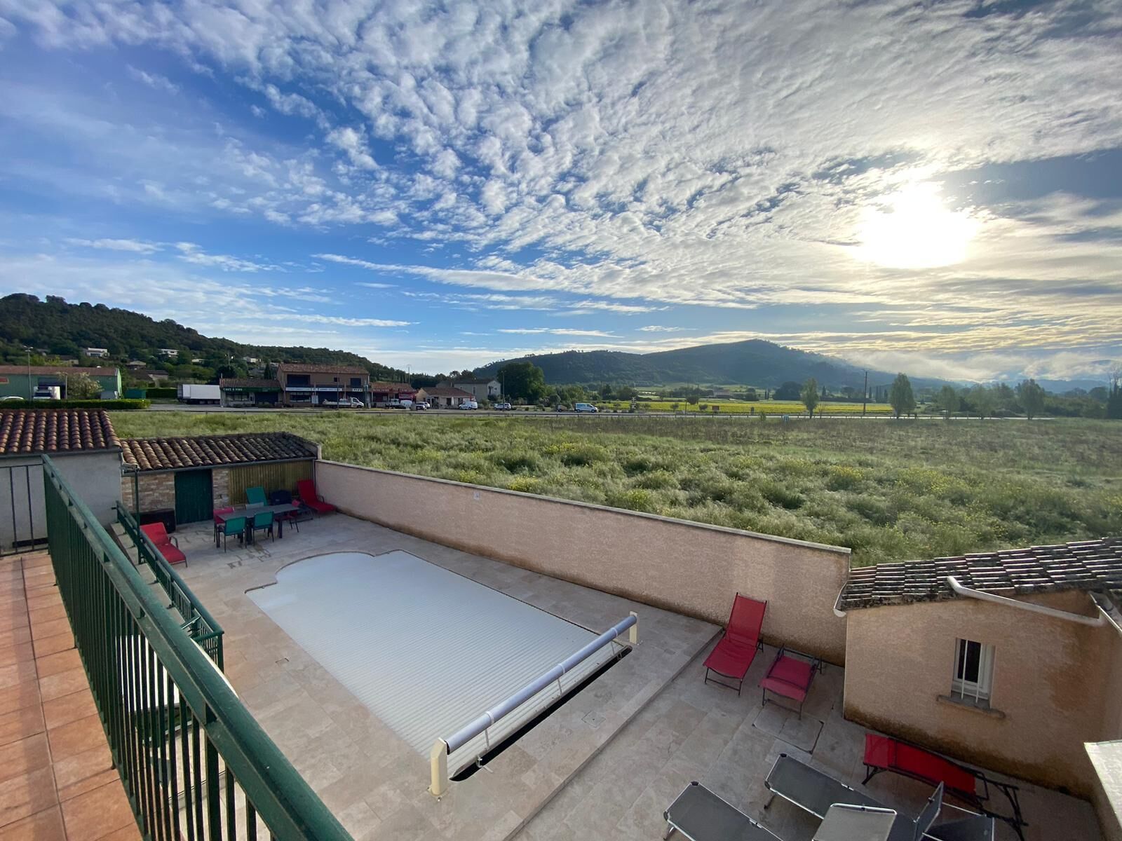 Una terraza en la azotea con una amplia superficie plana, baranda metálica y algunas sillas y mesas.