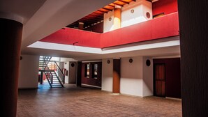 A spacious interior with a high ceiling, a staircase leading to an upper level, and a view of the outside through a window. - HOTEL ESPOR CA (Barinas)