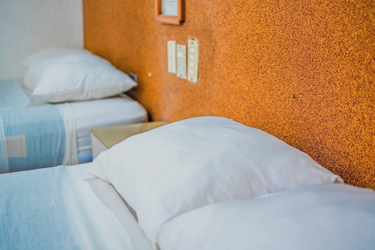 A hotel room with two beds, each with white bedding and pillows.