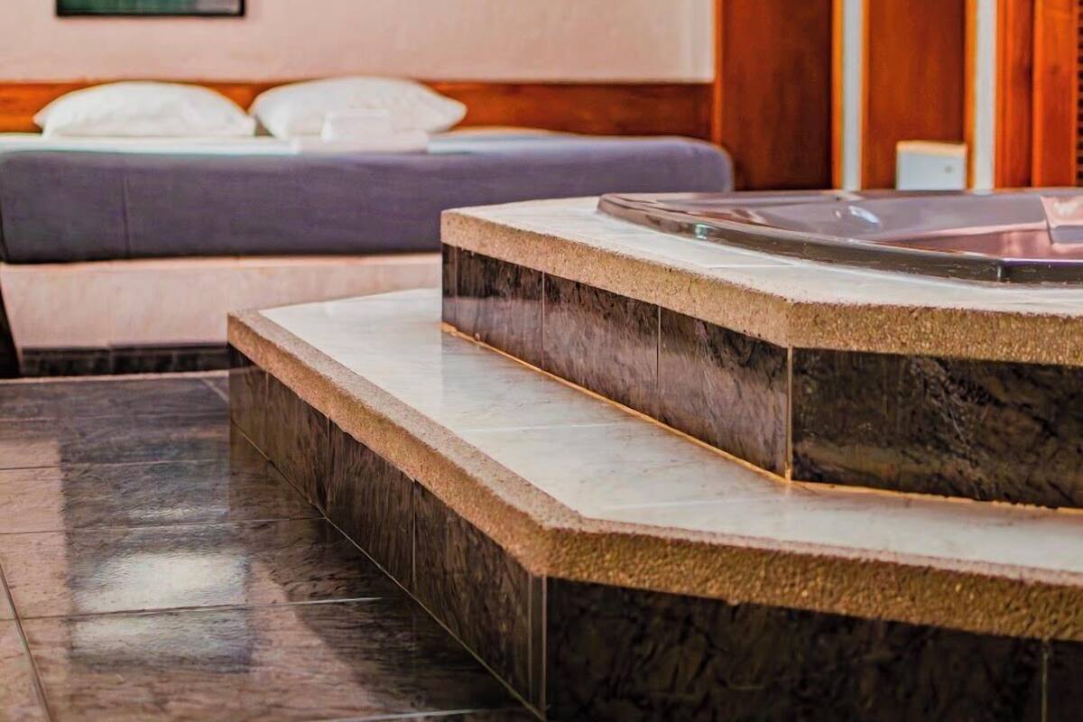 A hotel room with a bed, a small table with a tray, and a wooden wardrobe.
