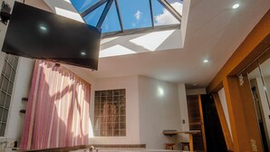 A modern bathroom with a skylight, a large bathtub, and a television mounted on the wall. - HOTEL ESPOR CA (Barinas)