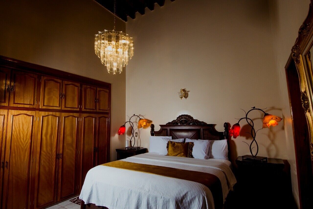 A bedroom with a large wooden wardrobe, a bed with white bedding, and a chandelier.