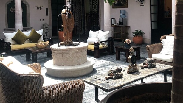 A courtyard with wicker furniture, a stone fountain, and a statue. - Hotel Posada San Miguel (Jerez de García Salinas)