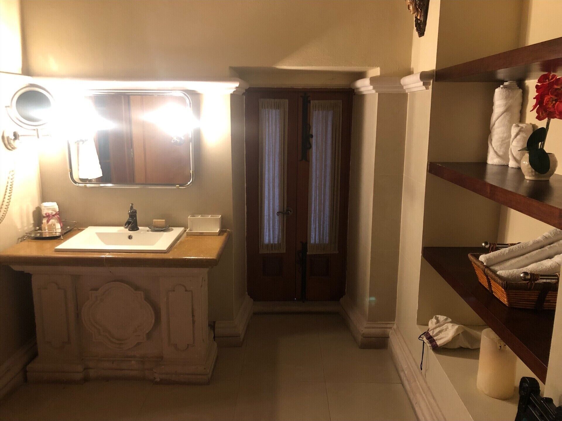 Un bagno con lavandino, specchio e mensole con asciugamani.