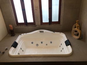 A large, rectangular hot tub with multiple jets, positioned in a room with a window and a decorative vase. - Hotel Posada San Miguel (Jerez de García Salinas)