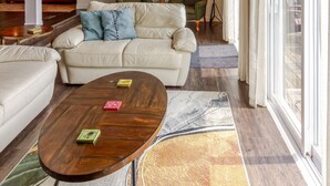 Un salón amplio con techo de madera, ventilador de techo, ventana grande y un sofá rojo.