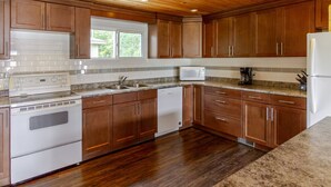 Una cocina con armarios de madera, una estufa blanca, lavavajillas y refrigerador.