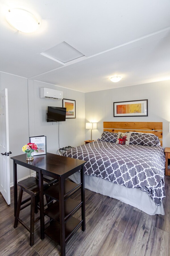 Ein ordentlich eingerichtetes Schlafzimmer mit Bett, Nachttisch, Lampe und einem kleinen Schreibtisch mit Stuhl.
