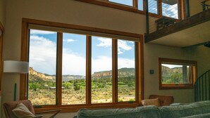 Ein Wohnzimmer mit einem großen Fenster und Blick auf eine gebirgige Landschaft.