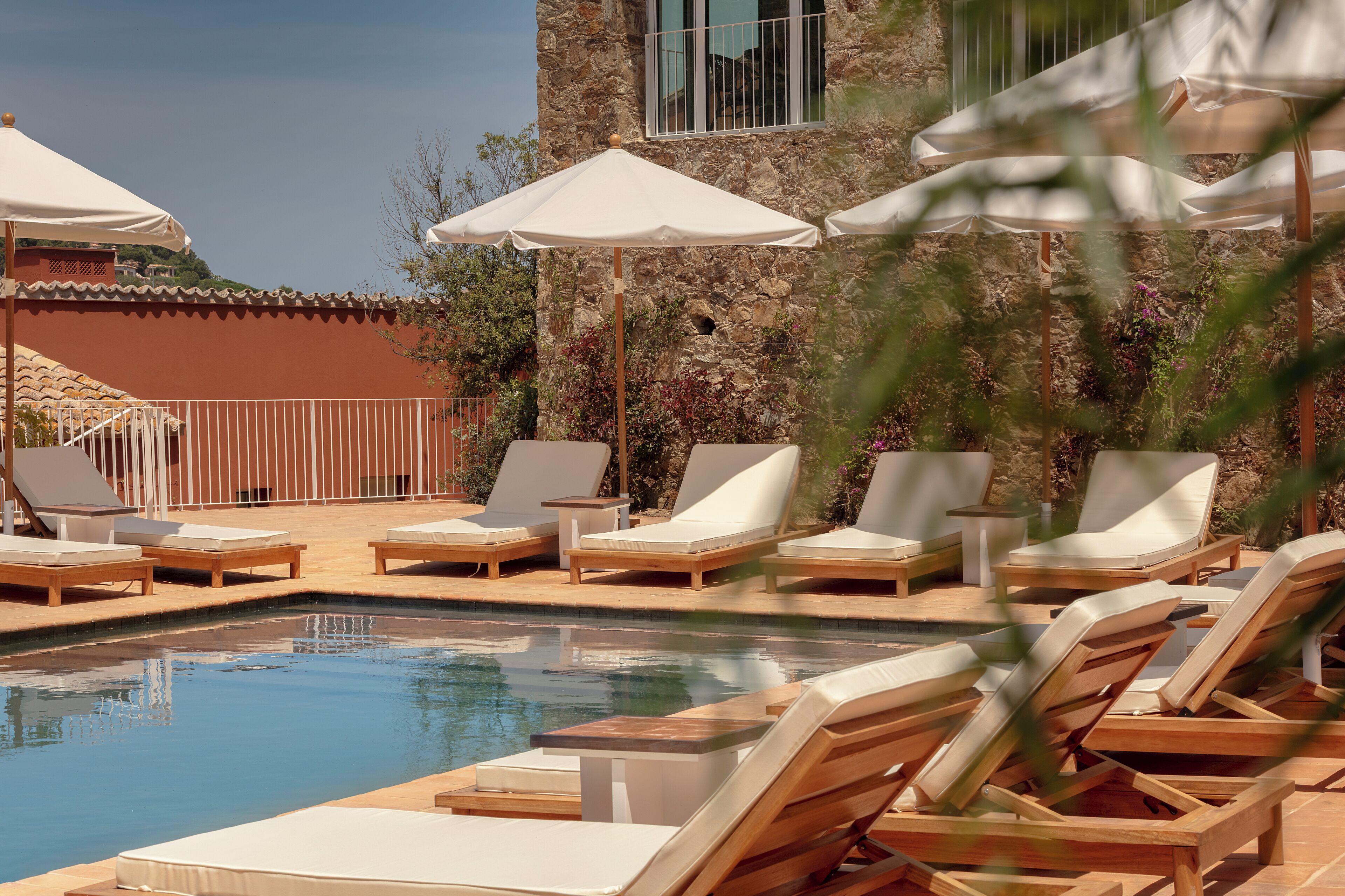 A pool area with lounge chairs and umbrellas.