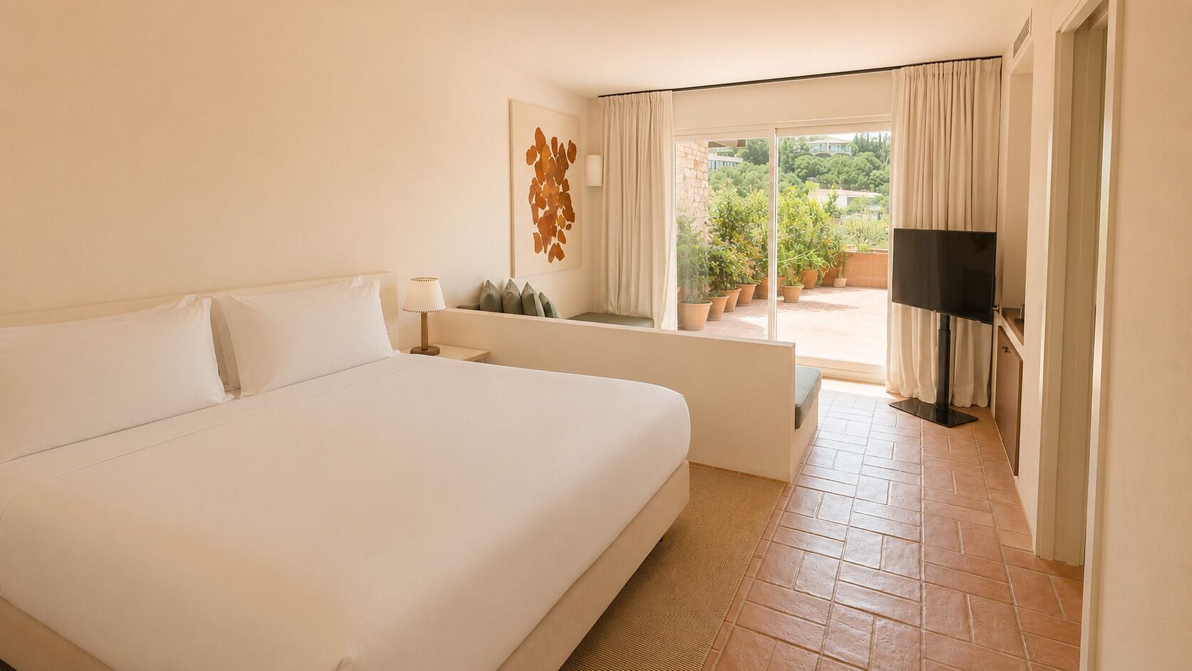 Una habitación de hotel con una cama grande, un sofá, un televisor y un balcón con plantas en macetas.