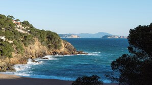 Eine Küstenlandschaft mit felsigen Klippen, einem Strand und freiem Blick aufs Meer.