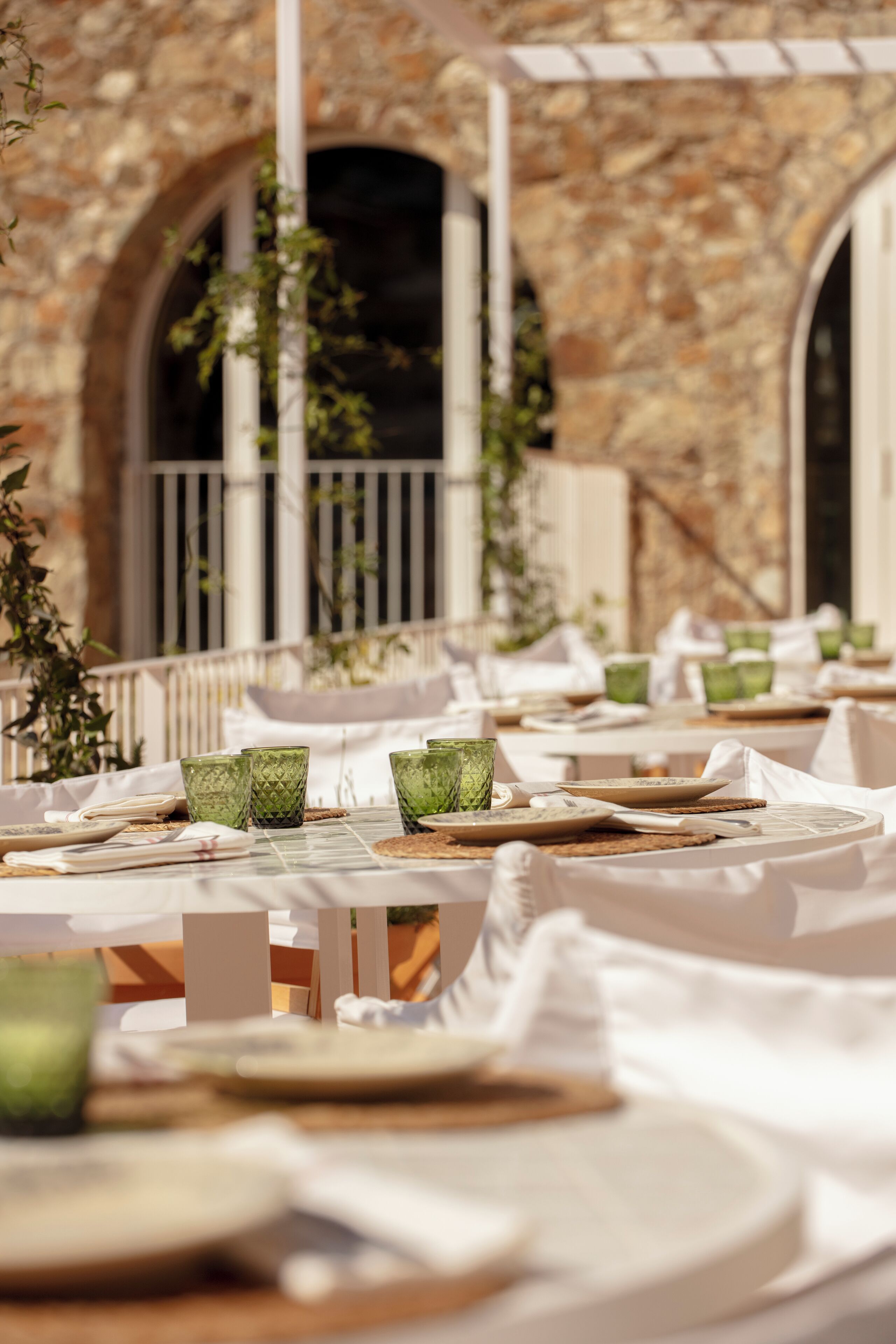A restaurant with outdoor seating, stone walls, and greenery.