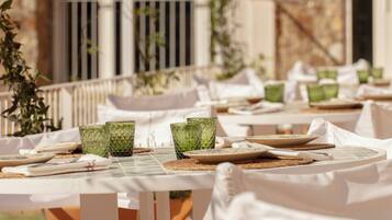 Un restaurante con terraza, paredes de piedra y vegetación.