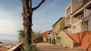 A narrow street with stone buildings, a tree with vines, and a clear sky. - Finca Victoria Hotel & Spa (Begur)