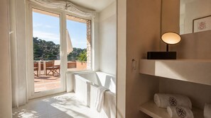 A balcony with a view of a garden and a patio, a white radiator, and a shelf with towels.