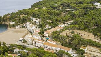 Vista aérea de un pueblo costero con edificios, una playa y abundante vegetación.