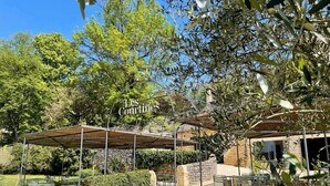An outdoor patio area with a pergola, stone walls, and green seating.