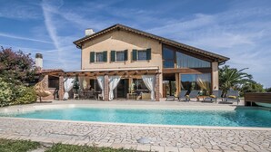 A two-story house with a swimming pool, outdoor seating, and a garden.