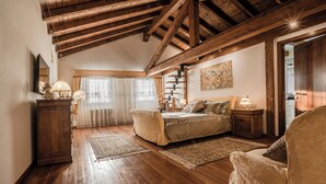 A bedroom with a wooden ceiling, a bed with a patterned bedspread, a nightstand, a chair, and a dresser.