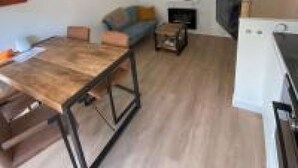 A modern living room with a wooden dining table, a sofa, and a TV. - Stylish House in Breda city center (Breda)