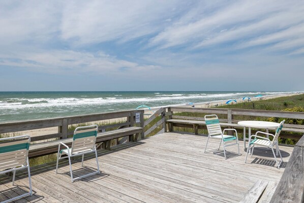 A wooden deck with a view of the ocean and beach.